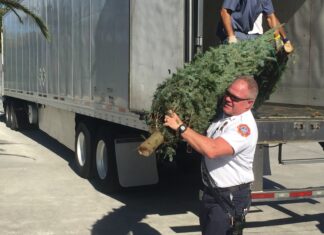 MONROE COUNTY FIRE RESCUE’S SEBBEN RETIRES FOLLOWING 30 YEARS OF SERVICE a man holding a christmas tree in front of a truck