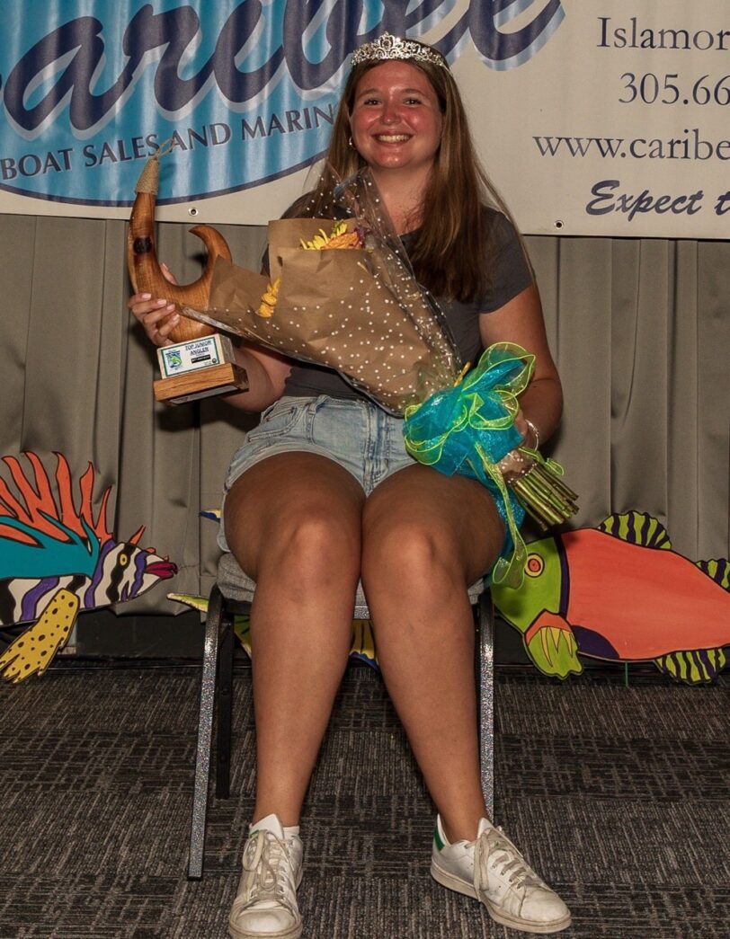 a woman sitting on a chair holding a trophy