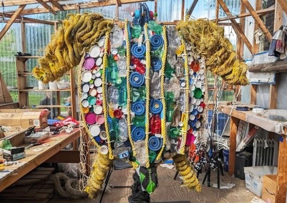 a man standing in a room with lots of items hanging from the ceiling