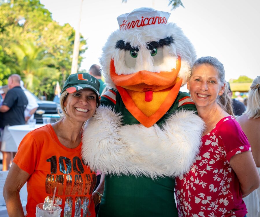 a couple of women standing next to a mascot