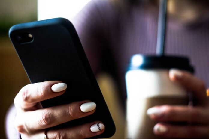 a woman holding a cup of coffee and a cell phone