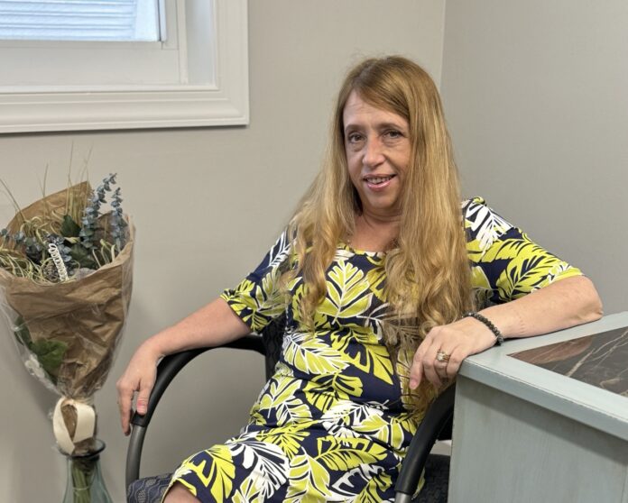 a woman sitting in a chair next to a vase of flowers