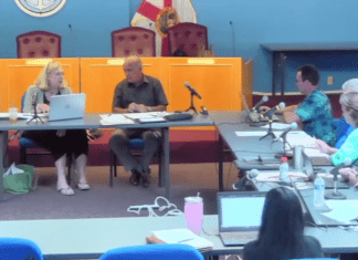 a group of people sitting at a table with laptops