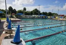 a large swimming pool with many lanes and blue umbrellas