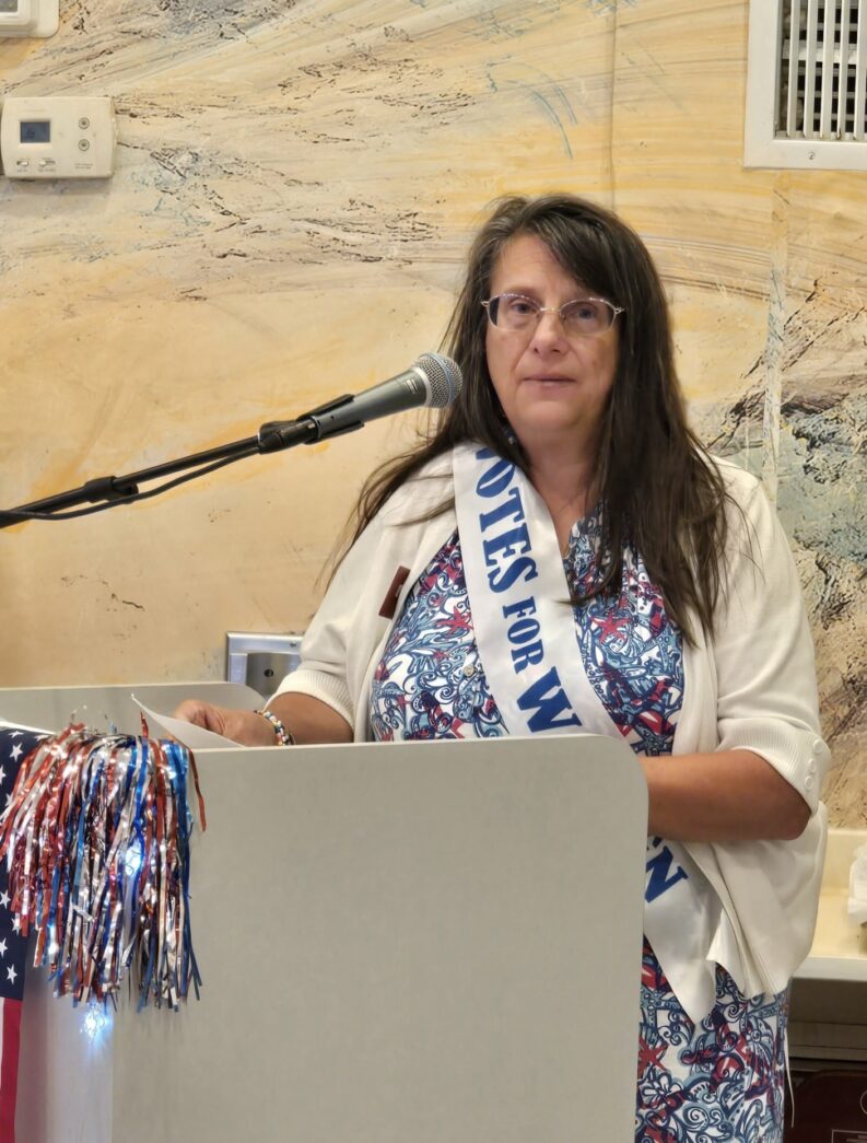 a woman standing at a podium in front of a microphone