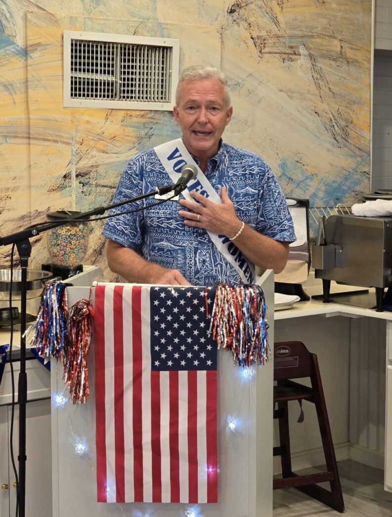 a man standing at a podium with an american flag on it