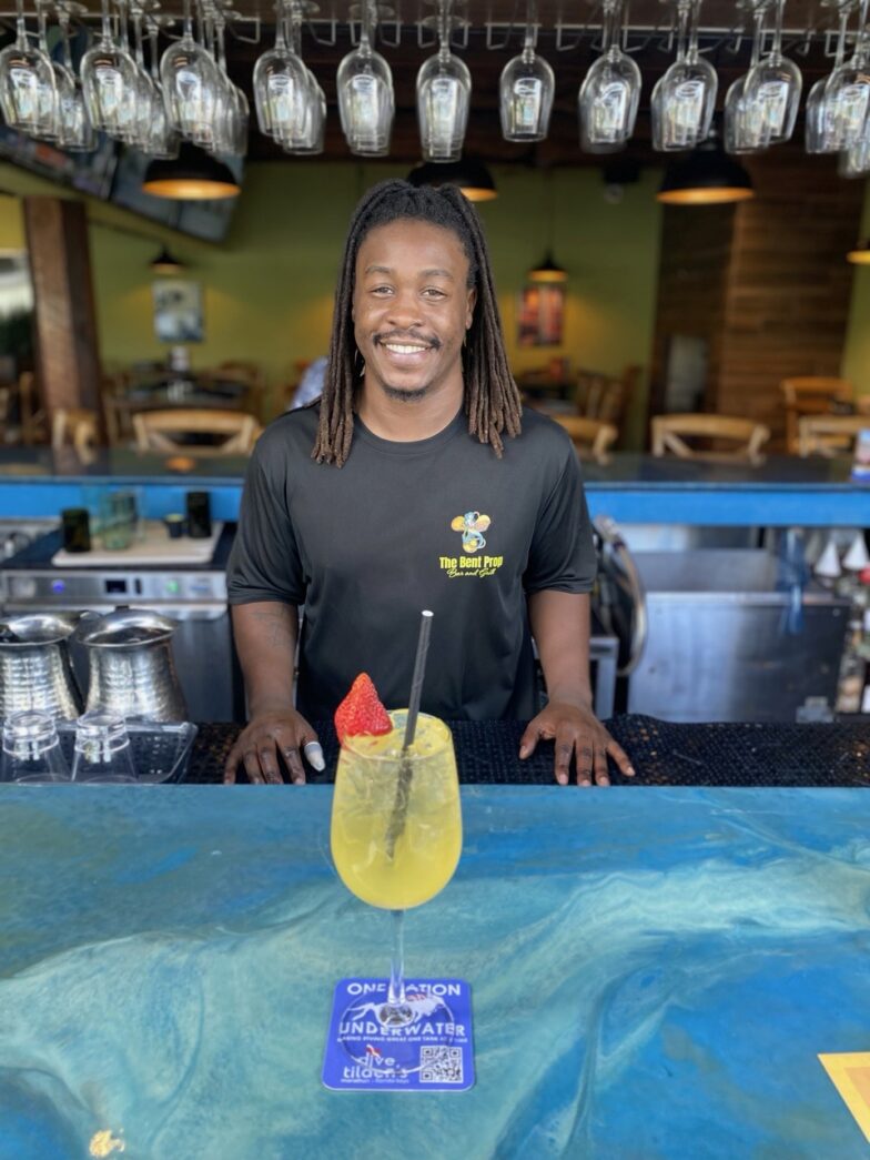 a man standing behind a bar with a drink in front of him