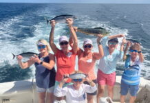 a group of people on a boat holding fish