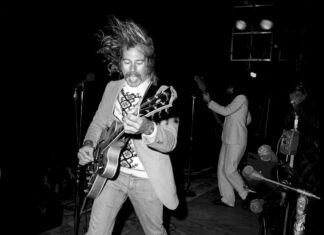 a black and white photo of a man playing a guitar