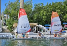 a group of people on small sailboats in the water