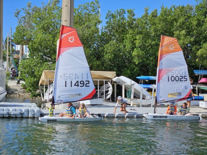 a group of people on small sailboats in the water