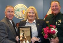 two men and a woman holding a framed picture