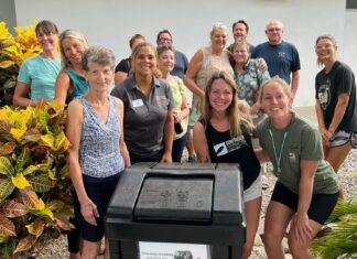 a group of people standing around a trash can