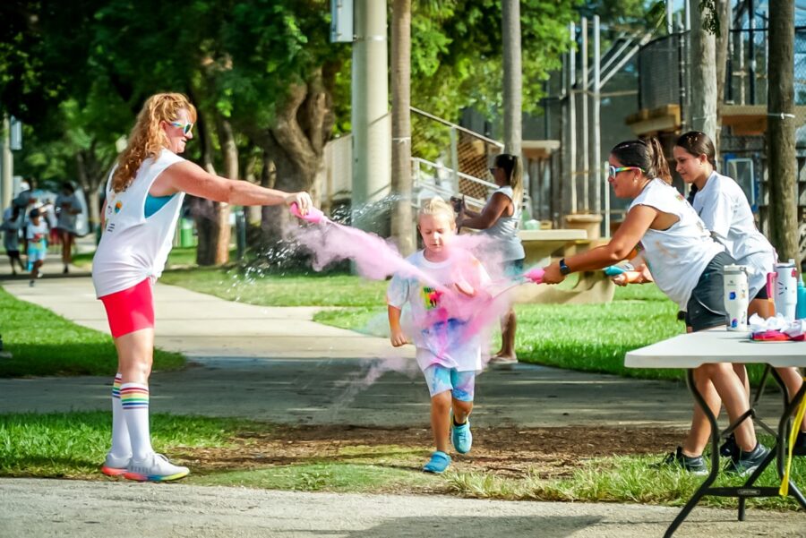 a woman and a little girl playing with a water cannon