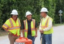 three men in safety vests standing next to a fire hydrant