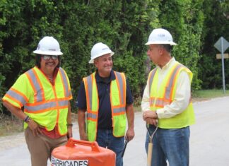 three men in safety vests standing next to a fire hydrant