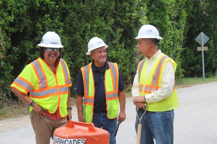 three men in safety vests standing next to a fire hydrant