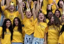 a group of girls in yellow shirts holding up their hands