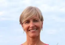 a woman in a pink top standing in front of the ocean