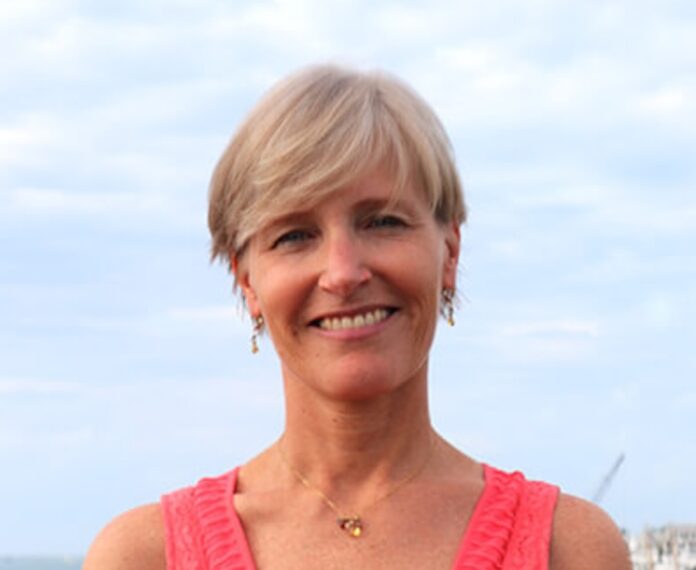 a woman in a pink top standing in front of the ocean