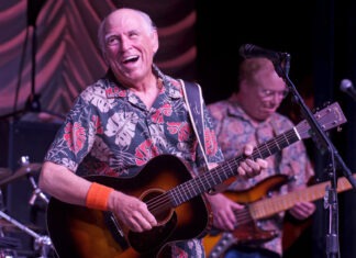 a man playing a guitar and singing into a microphone