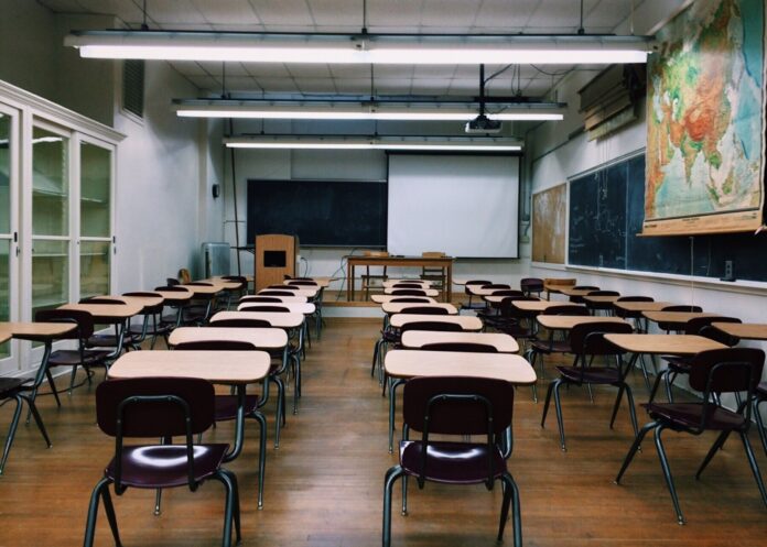 an empty classroom with desks and a chalkboard