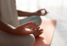 a person sitting in a lotus position on a yoga mat