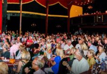 a large group of people sitting at tables in front of a stage