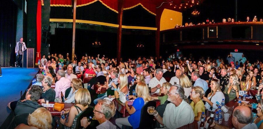 a large group of people sitting at tables in front of a stage