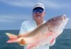 a man on a boat holding a large fish