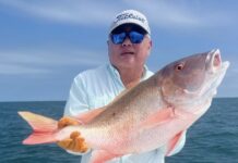 a man on a boat holding a large fish