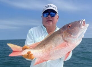 a man on a boat holding a large fish