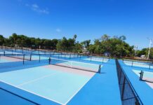 a tennis court with several tennis courts surrounded by trees