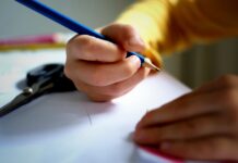 a person writing on a piece of paper with a pencil