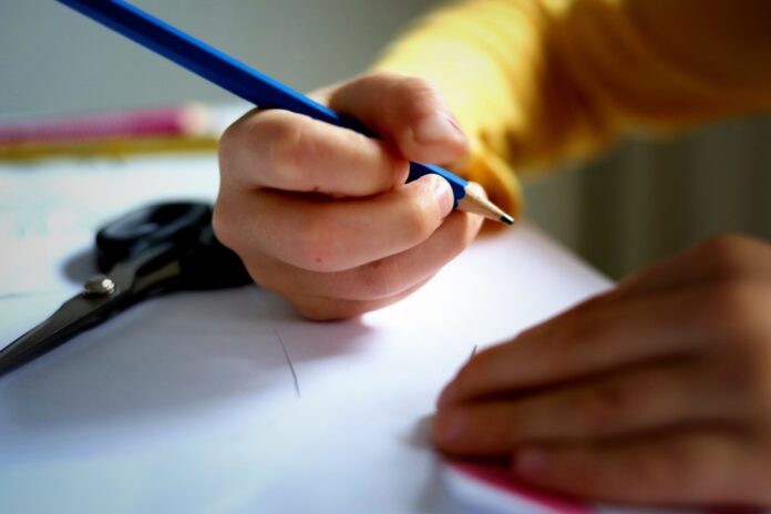 a person writing on a piece of paper with a pencil