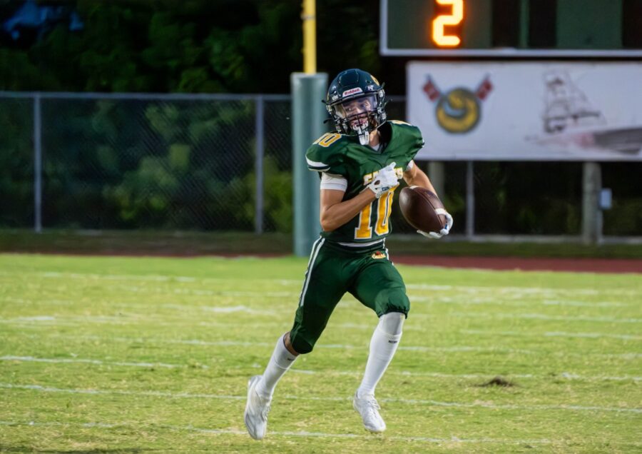 a football player holding a football on a field