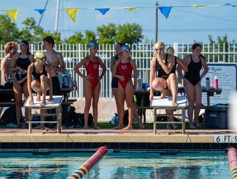 a group of women standing next to a swimming pool