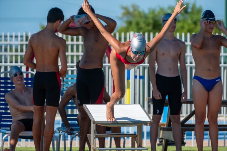 a group of people standing around a swimming pool