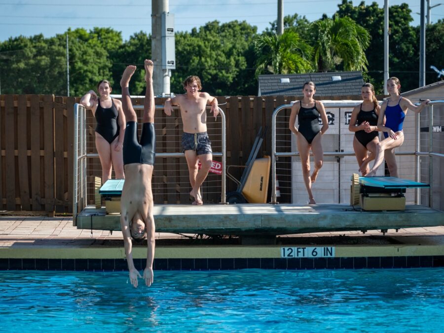 a group of people jumping into a swimming pool