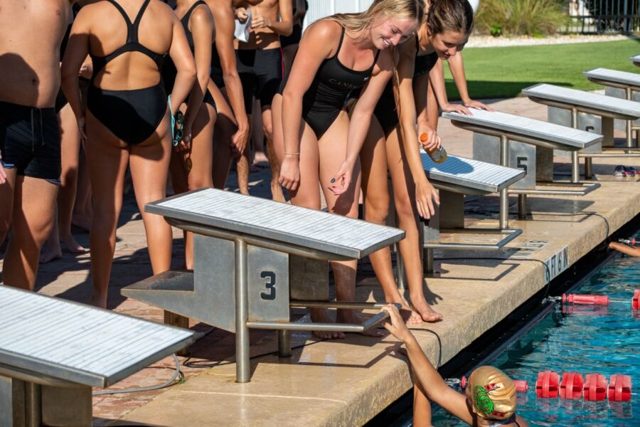 a group of people standing around a swimming pool