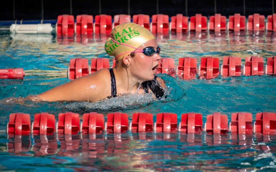 a woman swimming in a pool with a helmet on