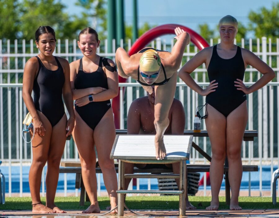 a group of women standing next to each other near a swimming pool