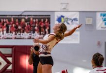 a woman jumping up to hit a volleyball