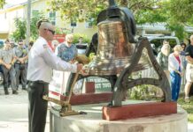 a man standing next to a large bell