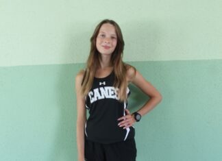 a girl in a black and white tank top standing in front of a wall