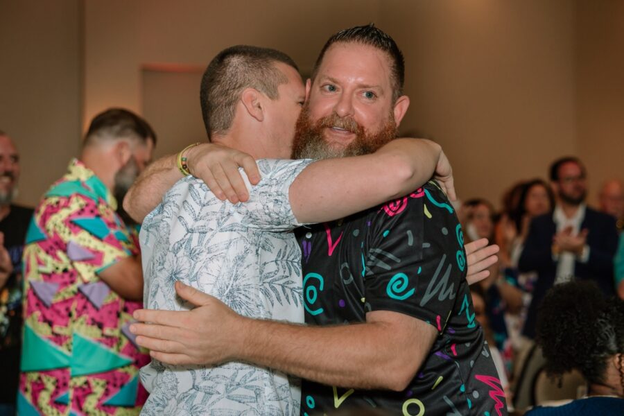 a couple of men hugging each other on a dance floor