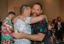 a couple of men hugging each other on a dance floor