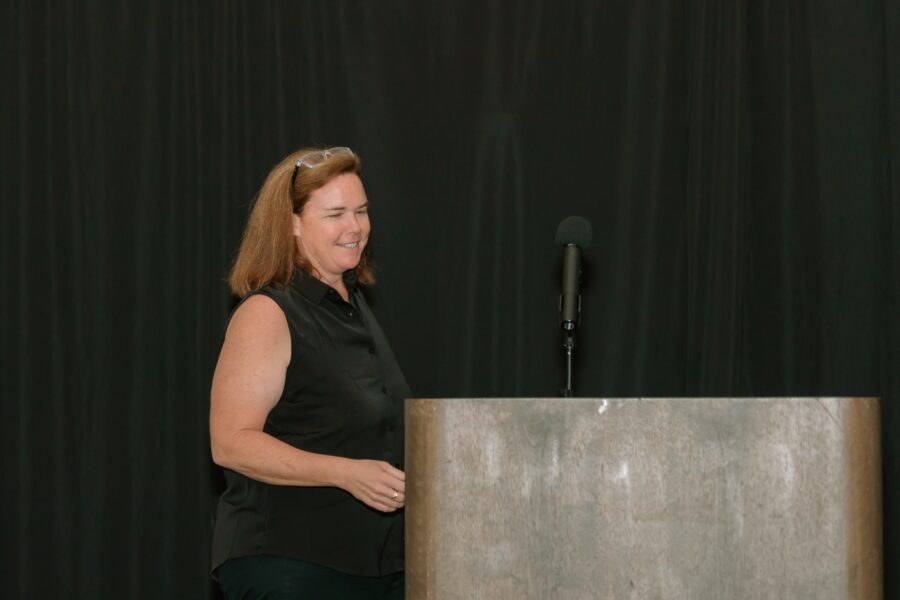 a woman standing at a podium in front of a microphone