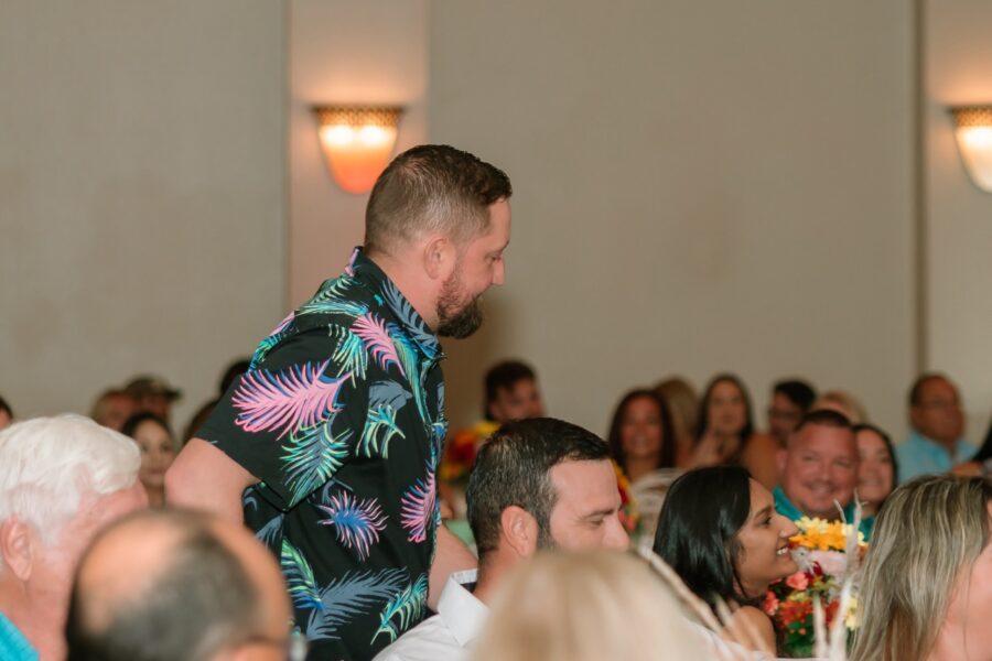 a man in a hawaiian shirt standing in front of a crowd of people