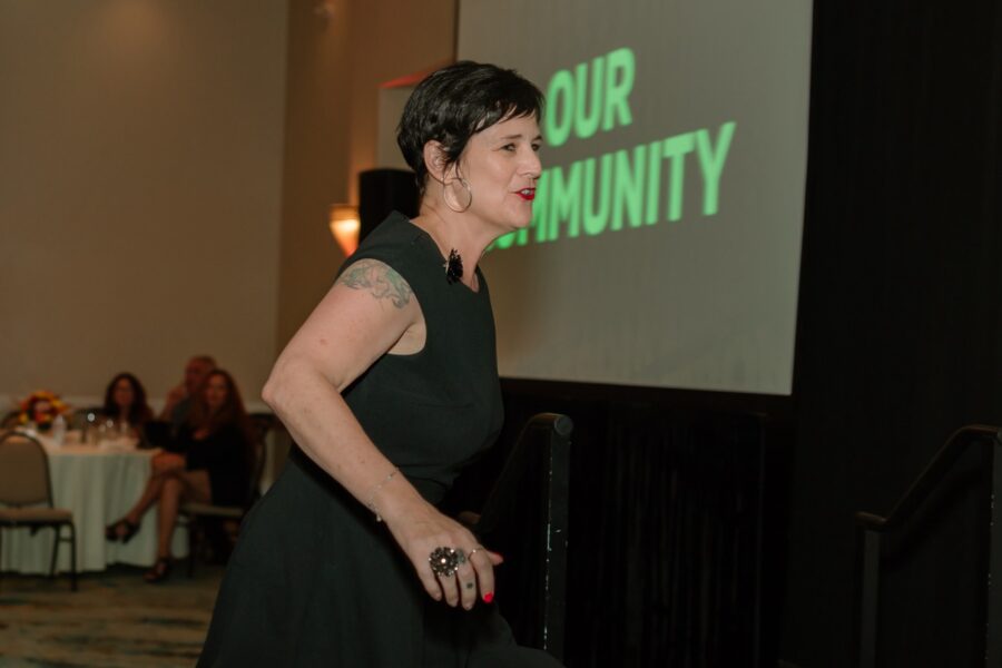 a woman in a black dress standing in front of a projector screen